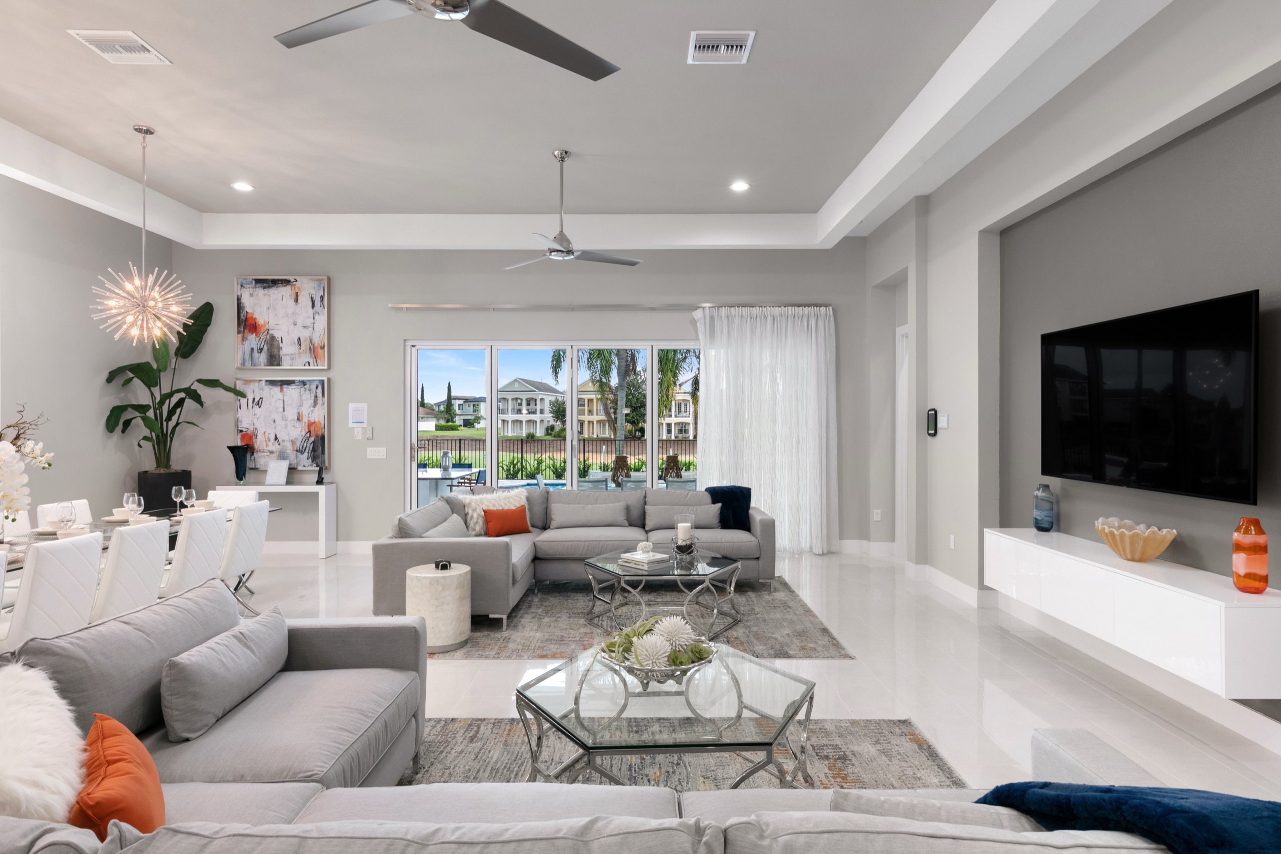 Open great room with a media wall, sectionals, and a starburst chandelier