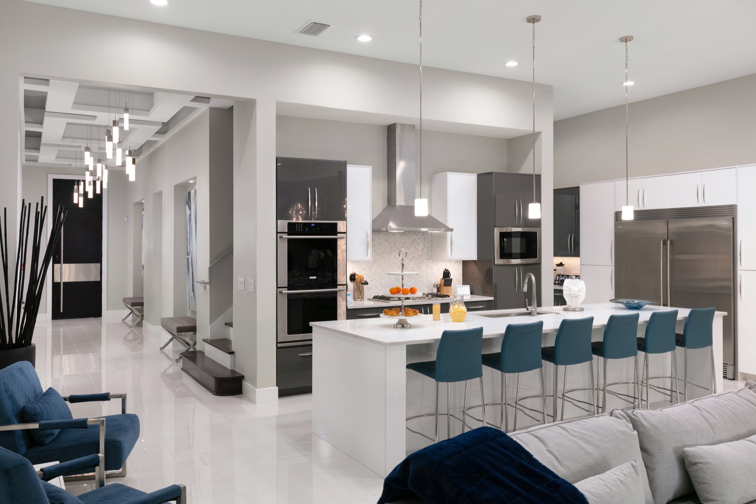 Dark-gloss chef's kitchen with a white waterfall island and blue stools