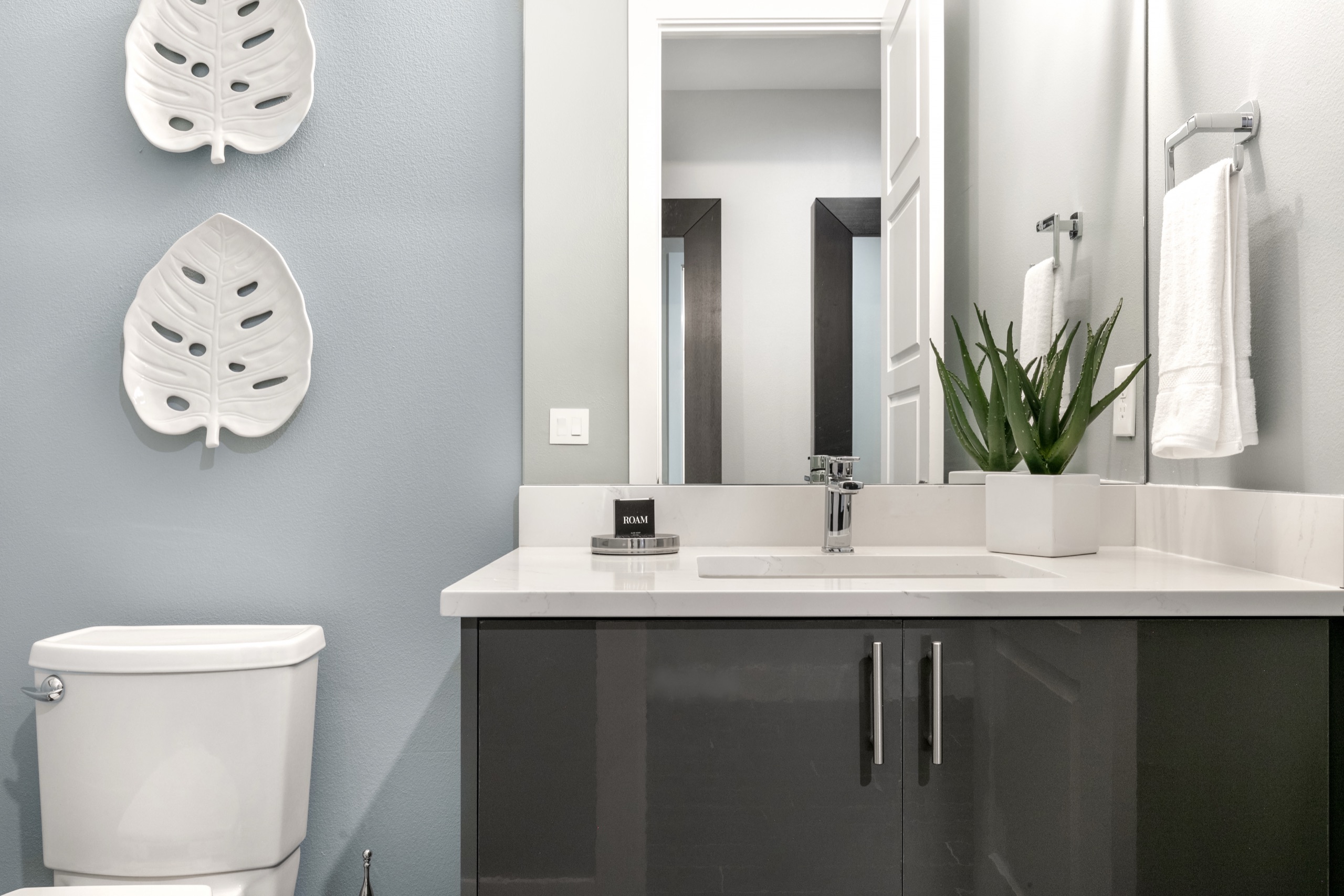 Powder room with a palm-leaf mirror and a gloss floating vanity