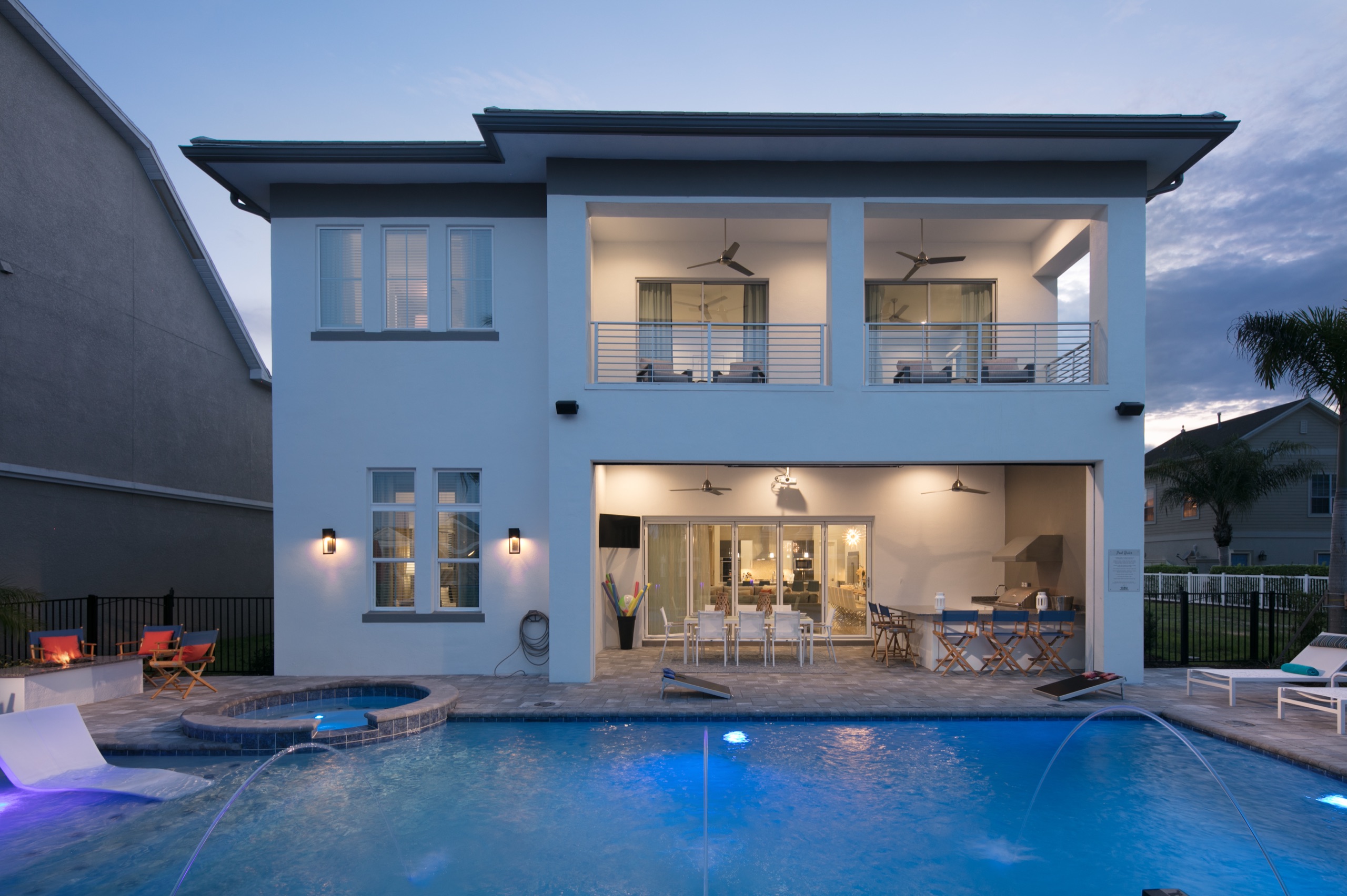 Rear elevation at dusk with the balconies lit and the pool's deck jets glowing