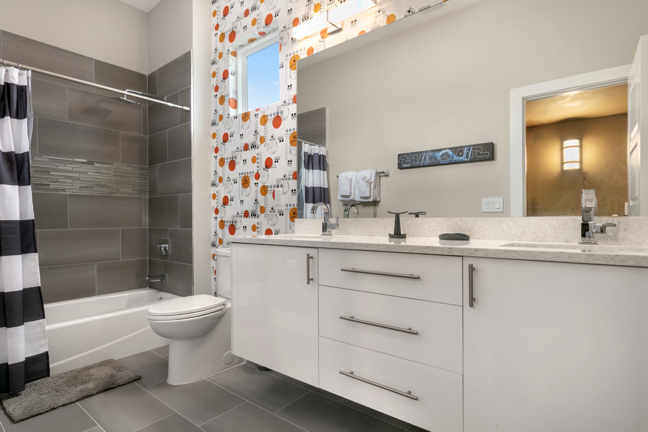 Galaxy kids' bath with droid wallpaper, a striped shower curtain, and a double vanity