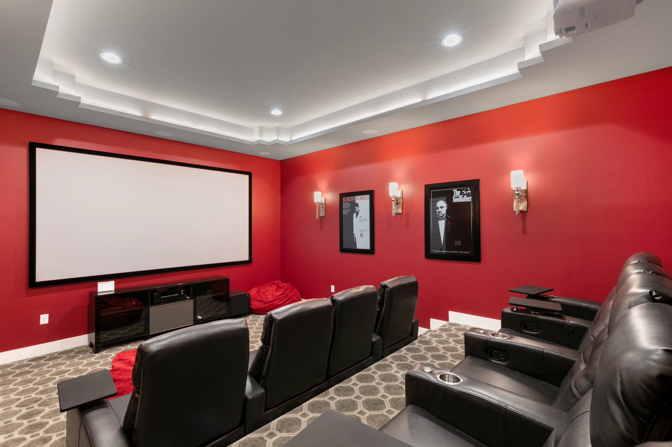 Red-walled home cinema with a wall-sized screen and tiered leather seating