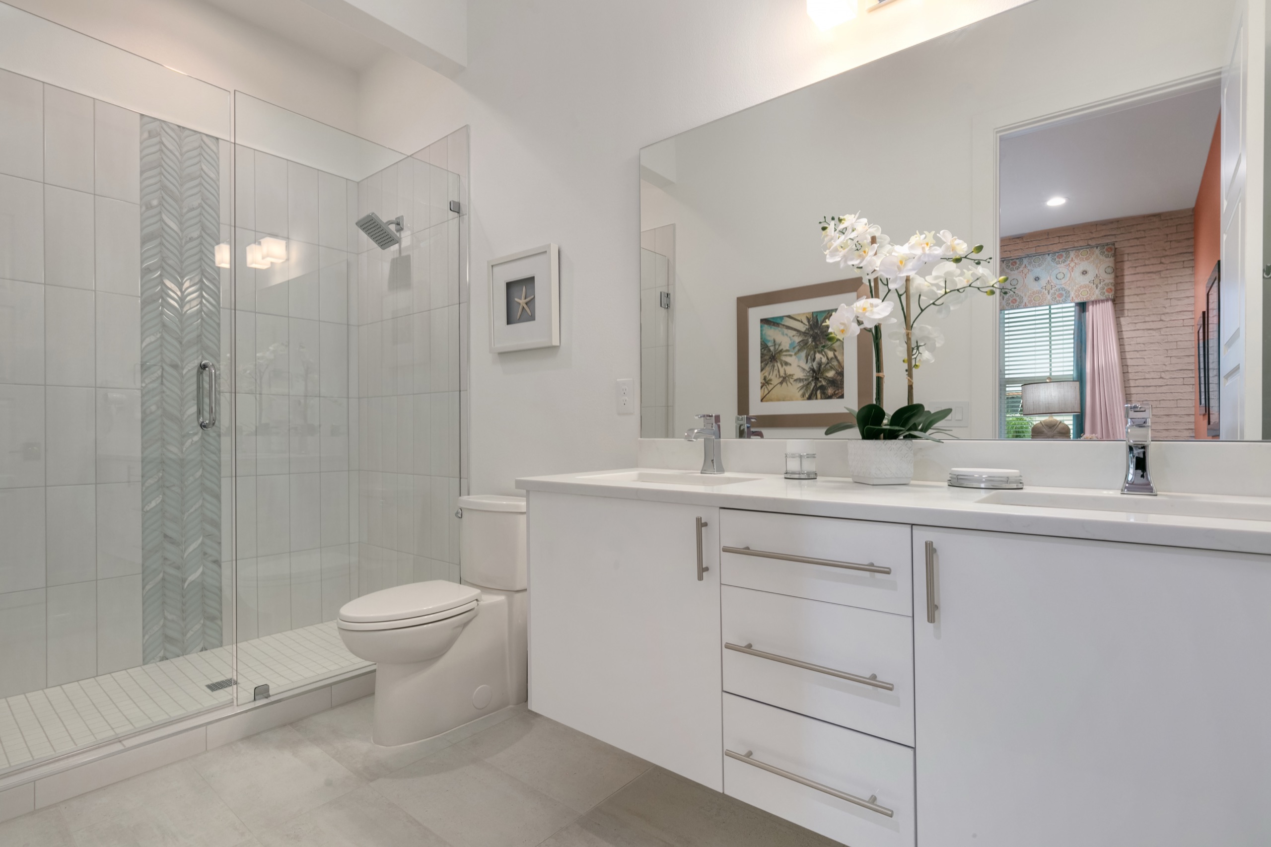 Havana suite bath in bright white with a glass walk-in shower, orchids, and palm-print art
