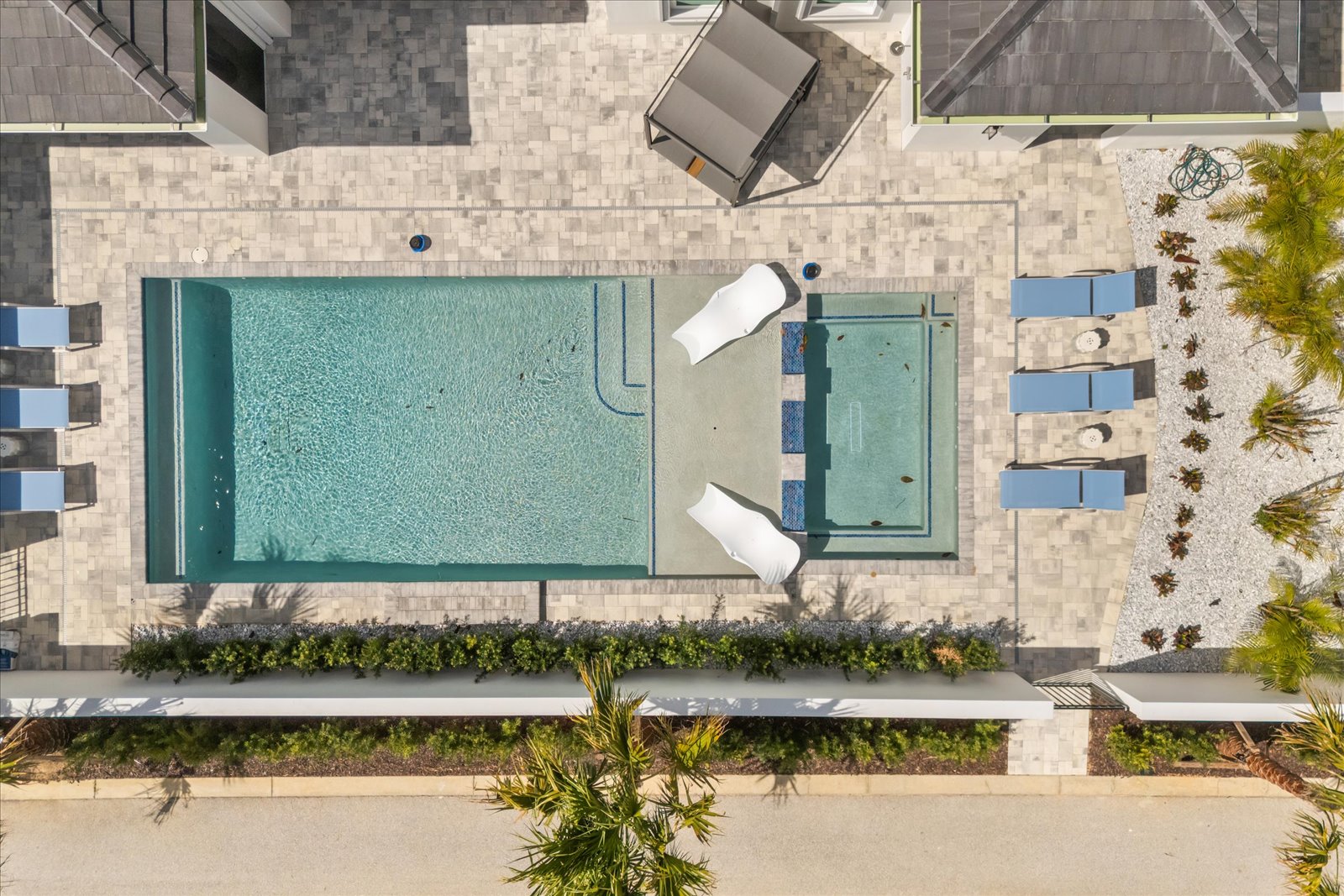 Resort pool and spa in honed travertine, with loungers and palms, seen from above