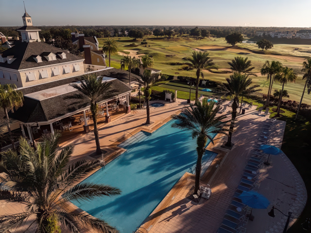 Whitemarsh Cove grounds at Reunion Resort — resort pool, clubhouse, and palms with the championship golf course beyond at golden hour