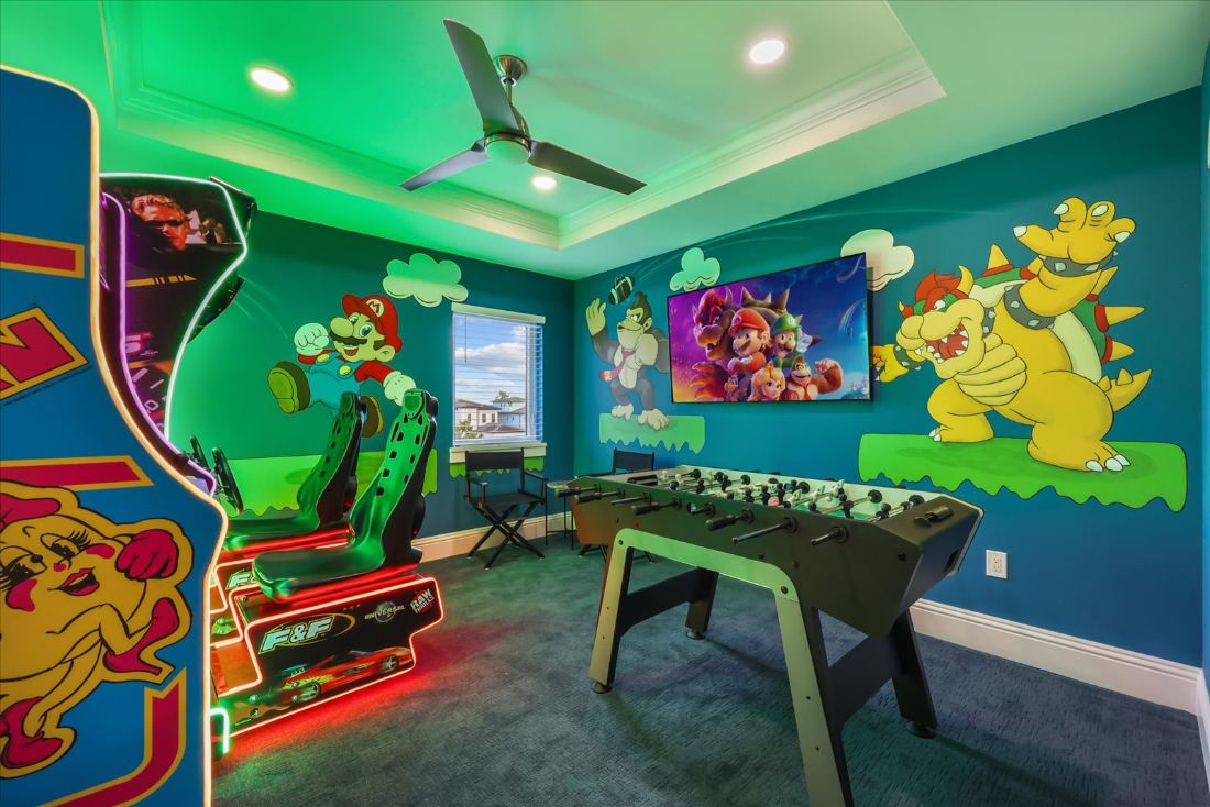 Game room with a hand-painted arcade mural, foosball, and neon-lit machines