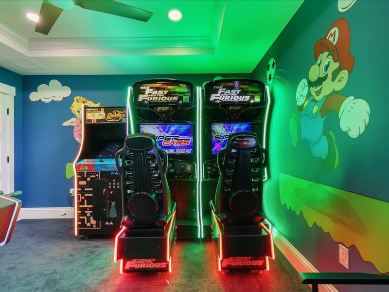 Twin racing simulator rigs beside the arcade wall