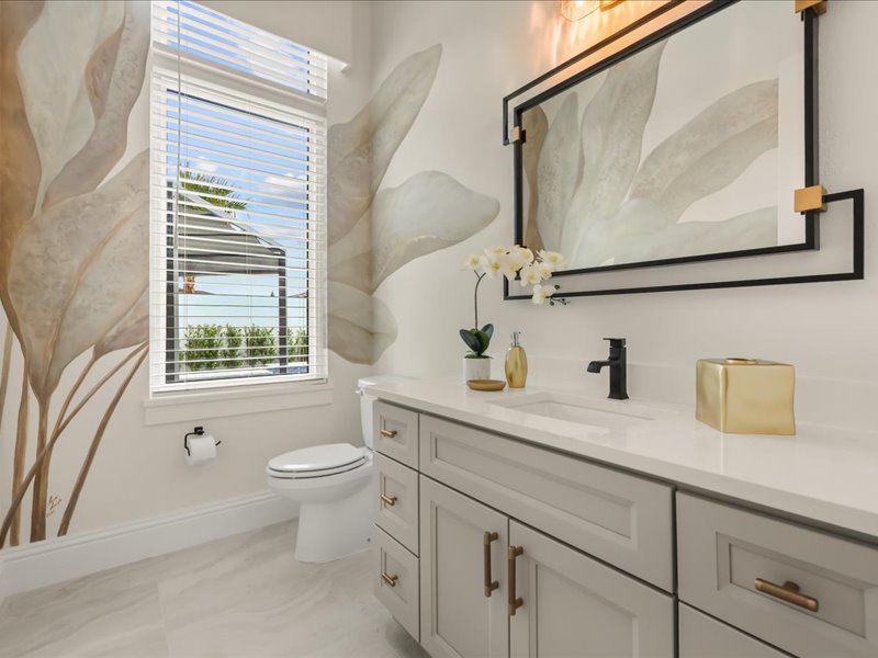 Vanity with botanical wallpaper and brass fixtures