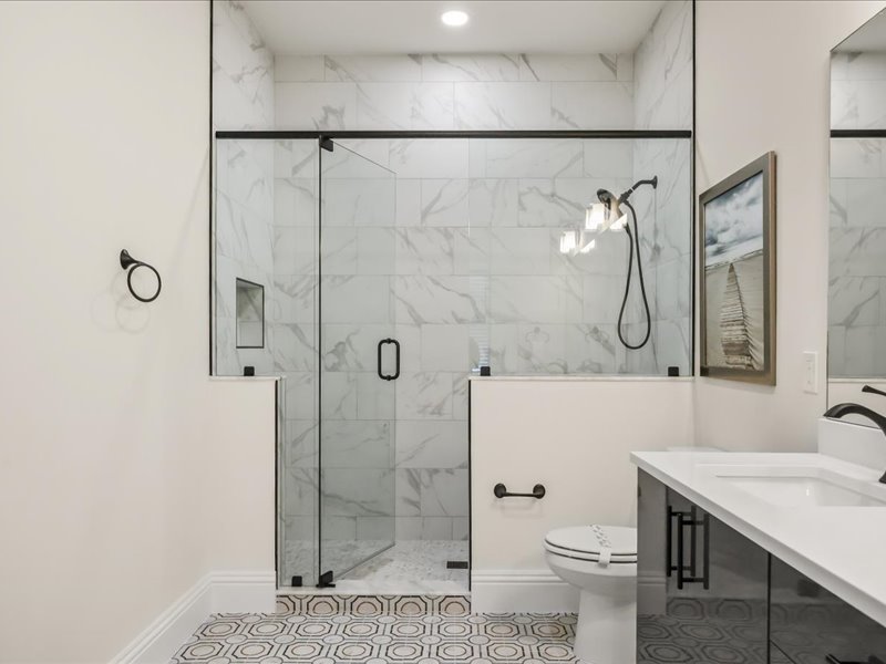 Guest bath in marble with a glass walk-in shower and dual vanity