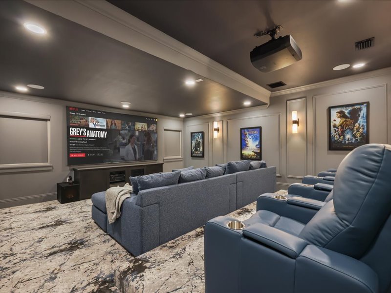Private cinema with a wall-sized screen, posters, and tiered seating