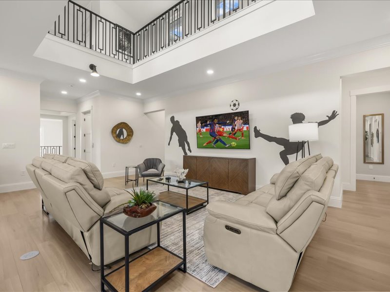 Two-story family lounge with a sports mural and double sectionals