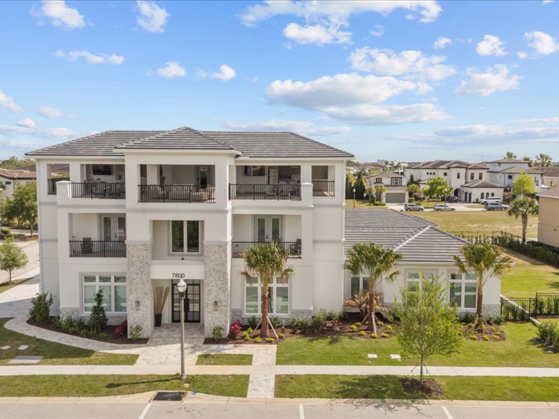 Front elevation of 7800 Whitemarsh Way with tile roof, balconies, and a stone base