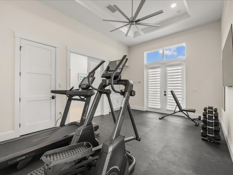Home gym with a treadmill and free weights by the window