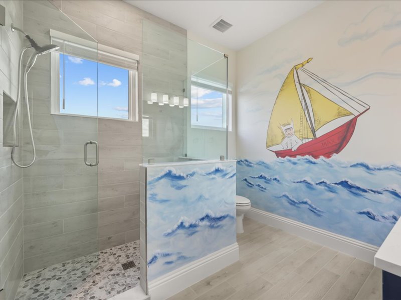 Children's bath with a hand-painted sailboat mural and a shower