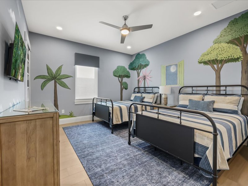 Children's room with twin beds and a painted palm-tree mural