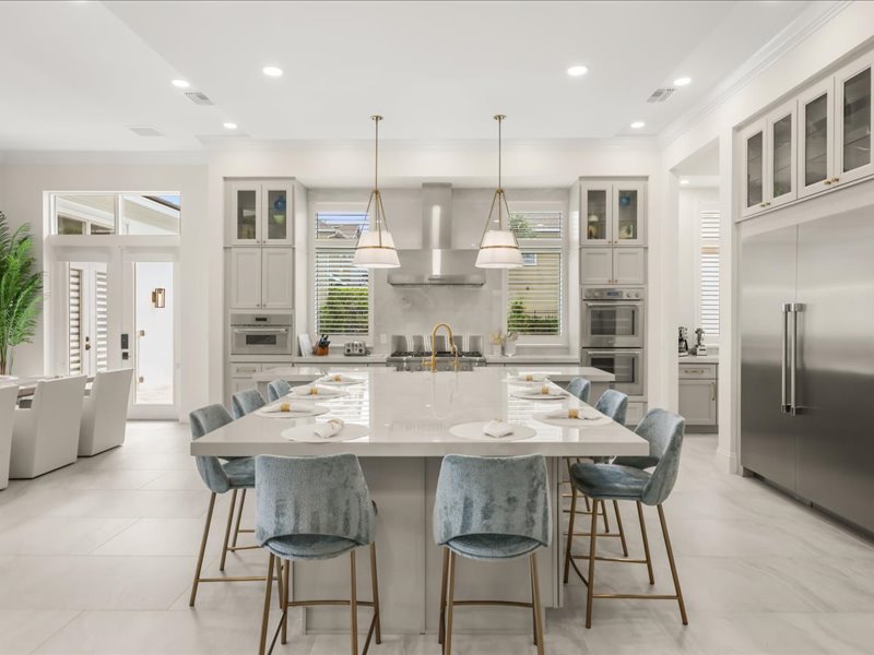 Kitchen island and dining table beneath linear pendants