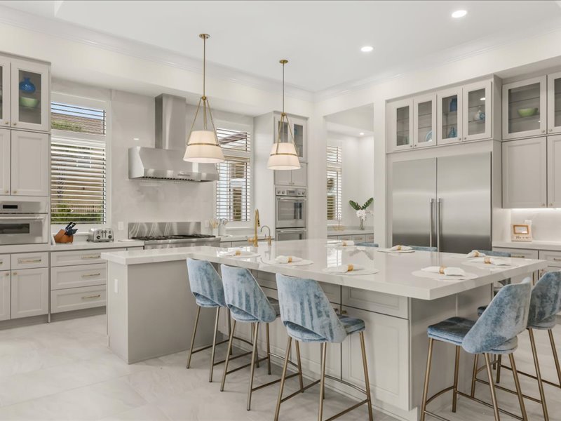 Chef's kitchen with a long marble island and blue counter stools