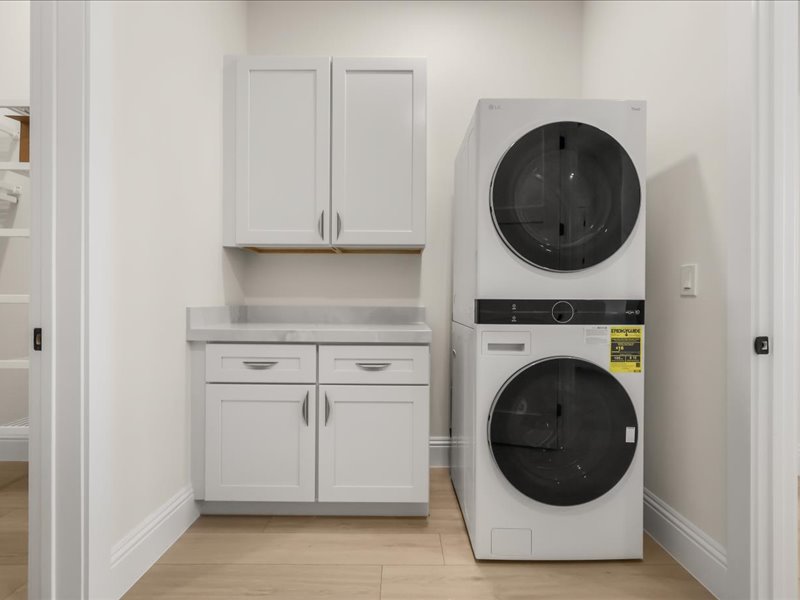 Laundry room with a stacked washer and dryer and cabinetry