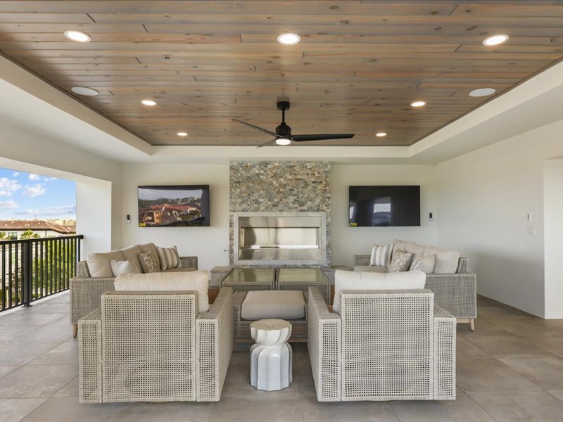 Covered loggia lounge with a linear fireplace and a mounted TV