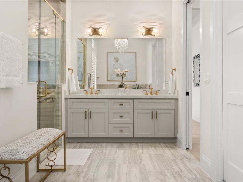 Dual marble vanities with a glass shower and a dressing bench